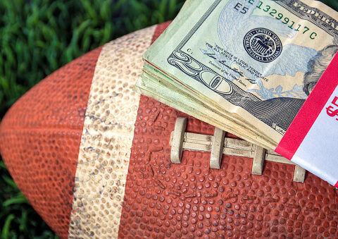 close up of wrapped money stack on football and green grass background