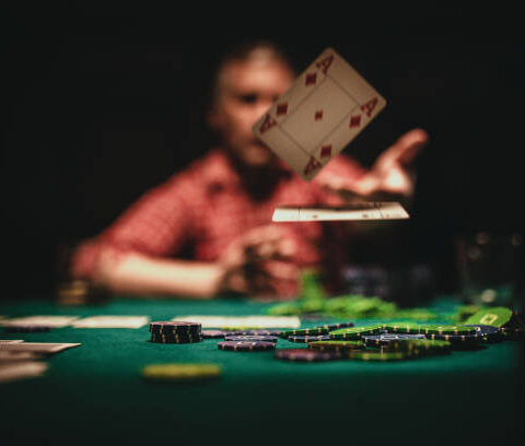 One mature man playing poker late by night, throwing playing cards on table.