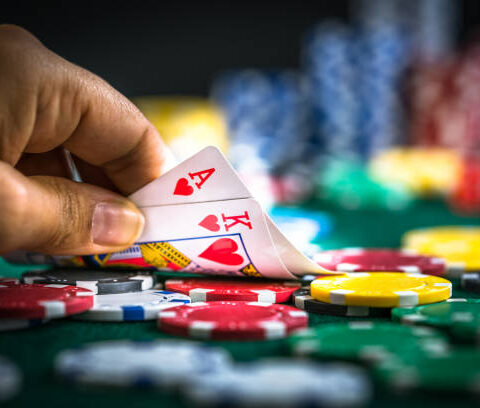 Gambling Hand Holding Poker Cards and Money Coins Chips
